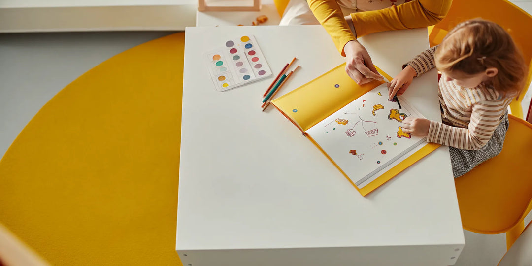 Homeschool table with colorful spelling workbooks and a mother helping a child practice spelling