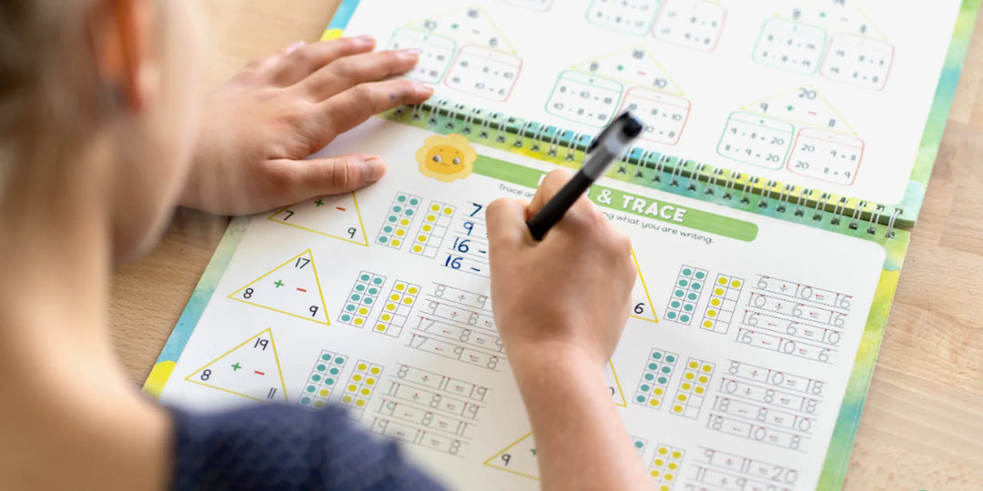 Child practicing handwriting in a grooved workbook at a wooden desk
