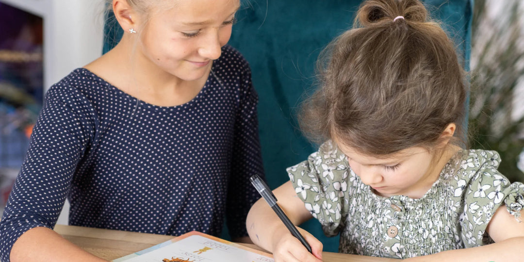 A young child practicing letter formation on a reusable grooved handwriting sheet